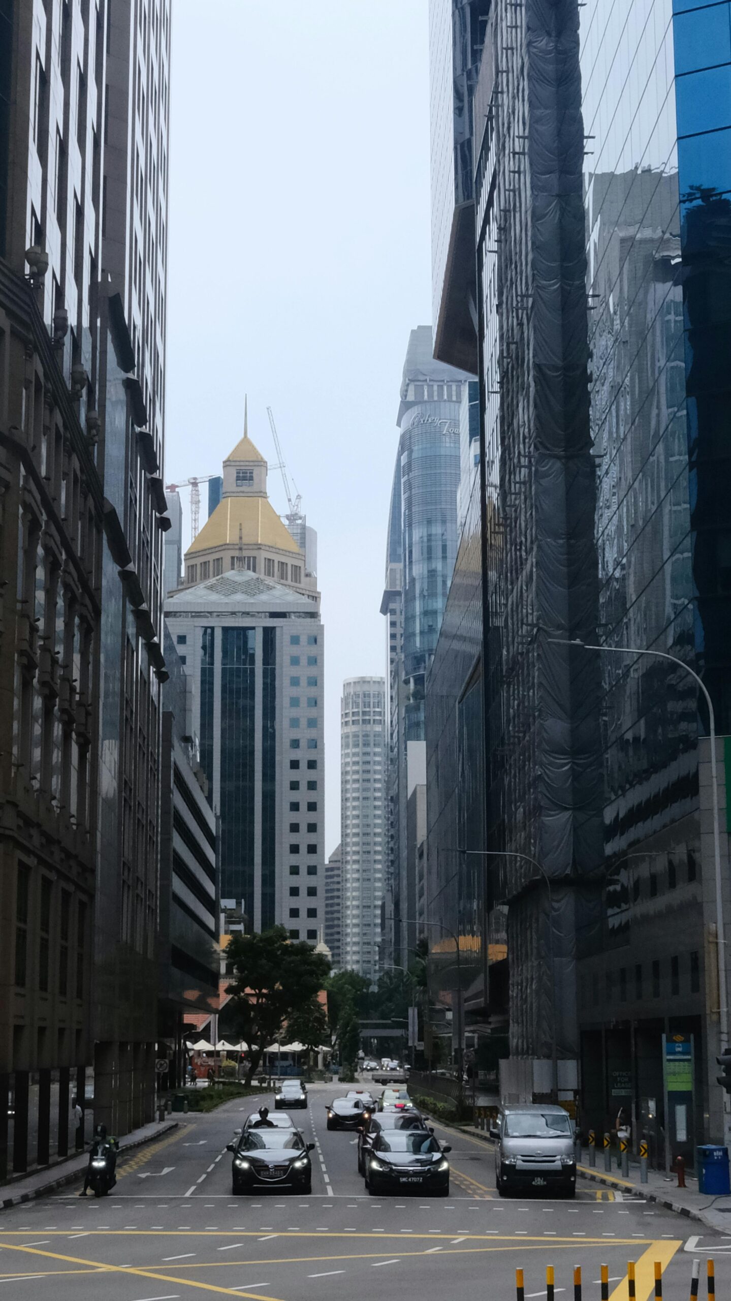 View of towering skyscrapers lining a busy street in Singapore urban landscape.